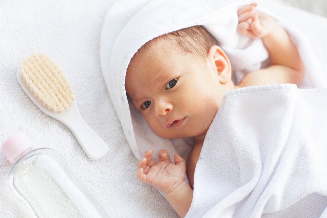 Ein Baby liegt eingewickelt in einem Handtuch.