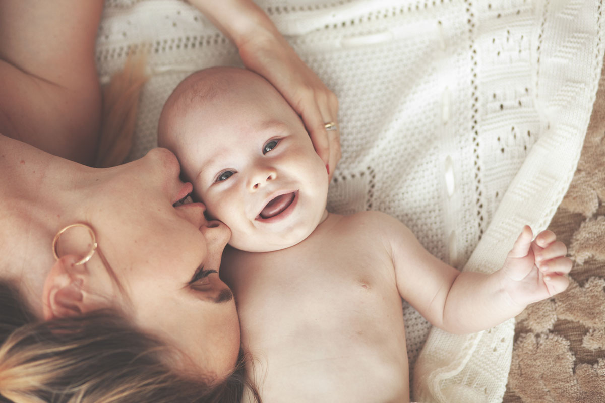 Mutter und Kind liegen entspannt auf einer Babydecke als Sinnbild für hilfreiche Tipps und den richtigen Umgang mit Neurodermitis bei Babys und Kindern